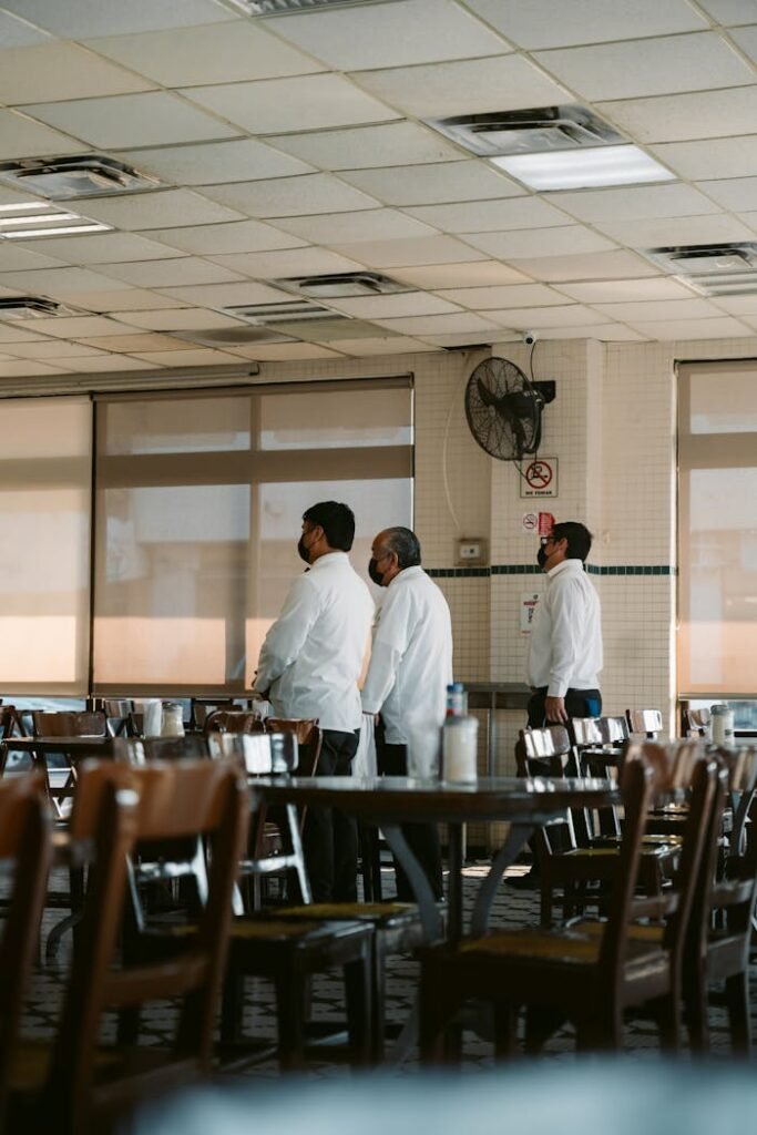 Three waiters standing in a restaurant in Veracruz, Mexico, wearing white uniforms.